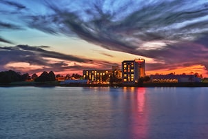 A hotel with a modern architectural design, situated by a body of water, reflecting the surrounding landscape.