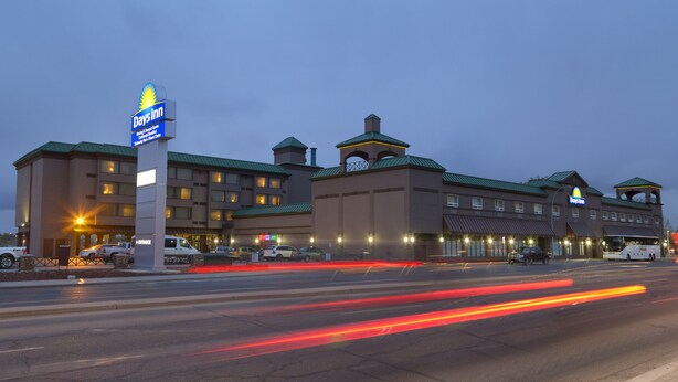 A Days Inn hotel with a large sign, multiple buildings, and a parking lot. - Days Inn by Wyndham Calgary South (Calgary)
