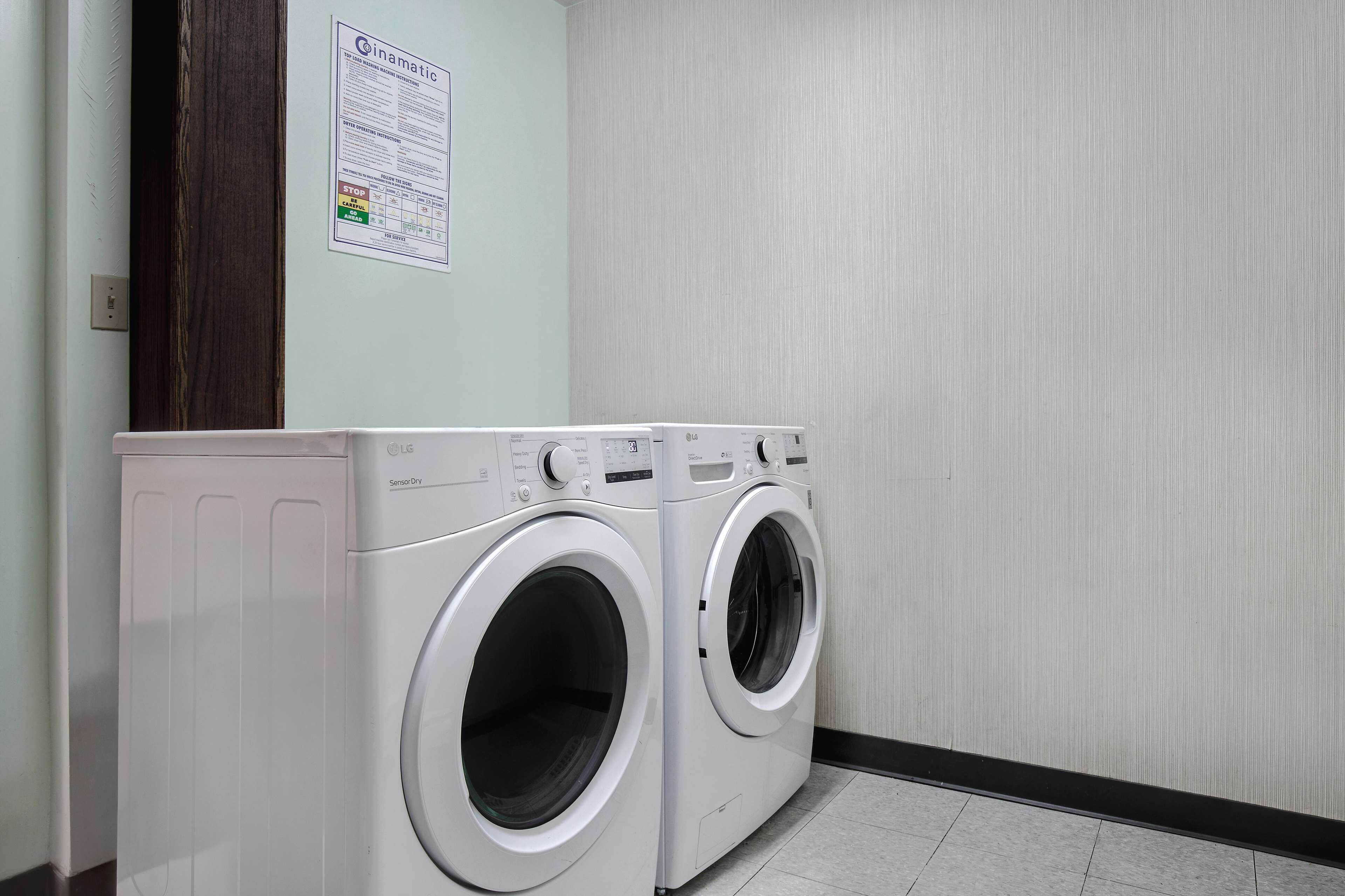 A laundry room with two front-loading washing machines and a wall-mounted instruction sign.