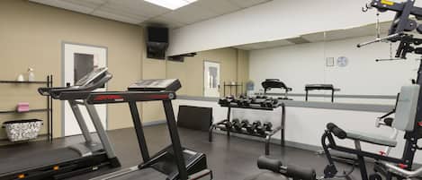 Ein Fitnessstudio mit Laufbändern, Hanteln und Krafttrainingsgeräten.