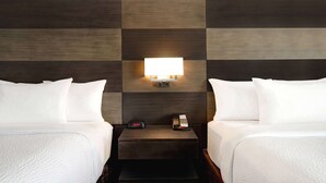 A hotel room with two beds, a nightstand with a clock and phone, and a wall-mounted light fixture. - Days Inn by Wyndham Calgary South (Calgary)
