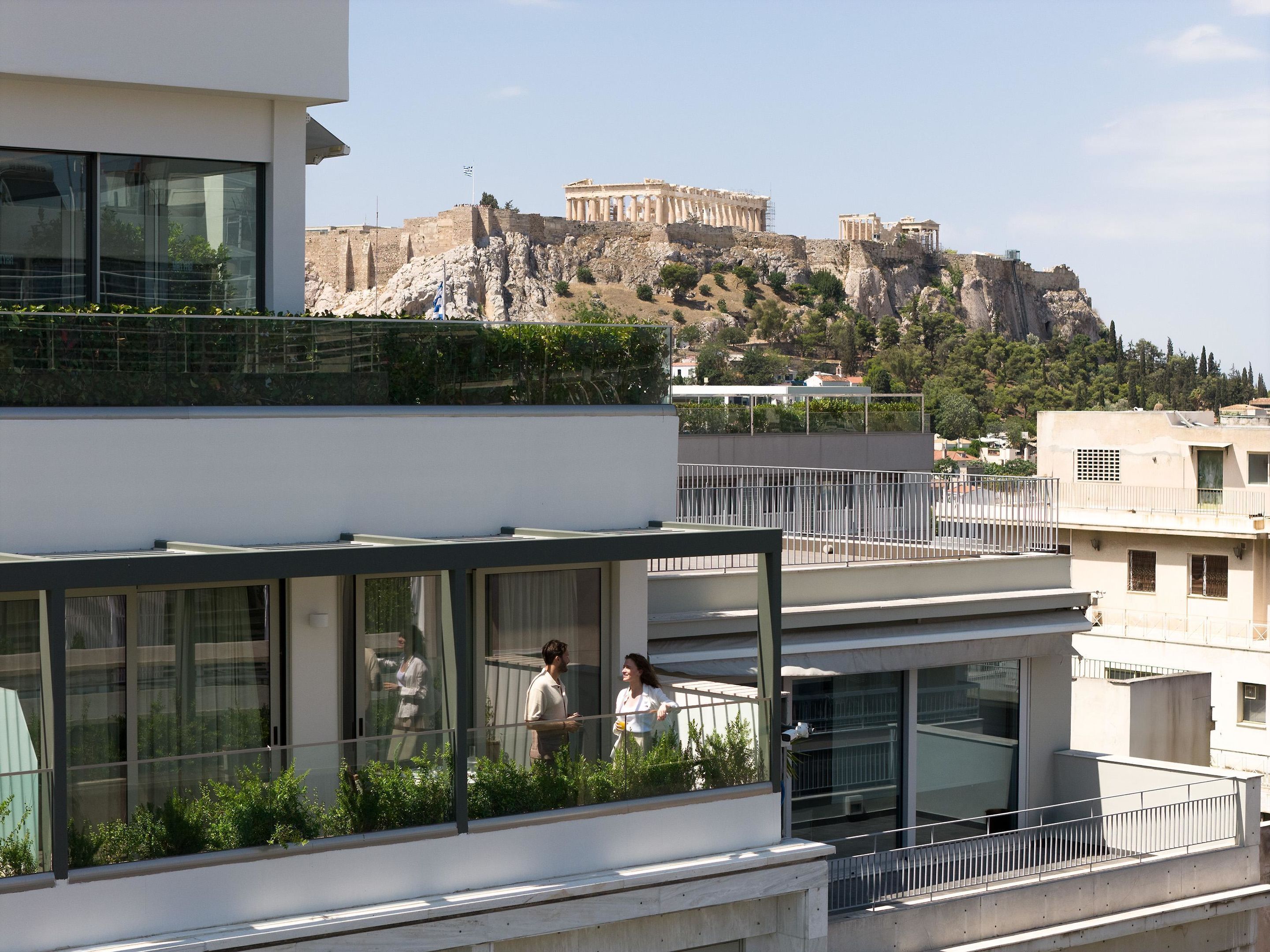 A modern building with a balcony overlooking ancient ruins.