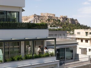 A modern building with a glass balcony overlooking a historic site.