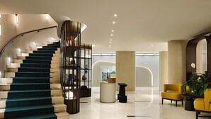 A modern interior with a spiral staircase, a reception area, and a seating area with yellow chairs.