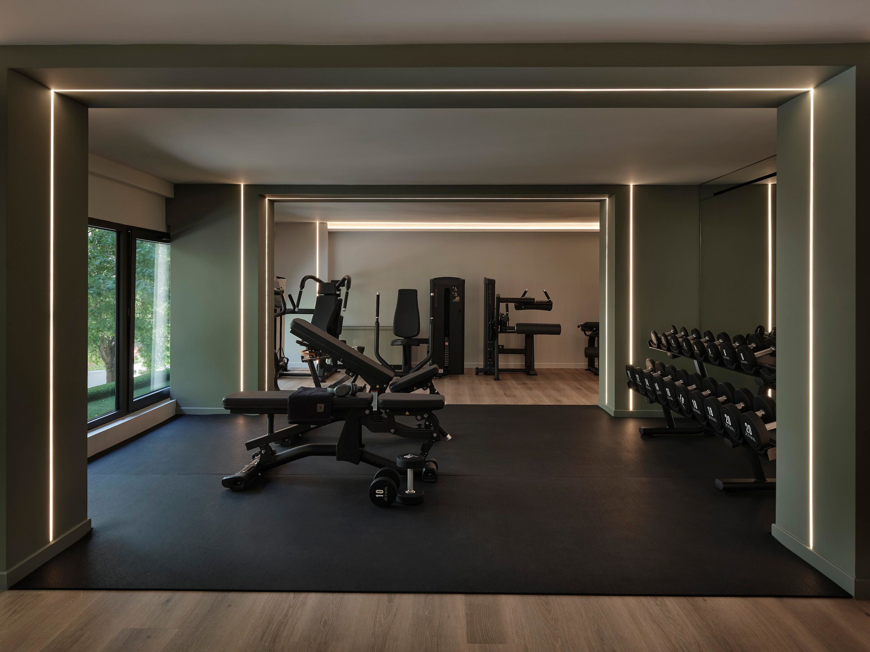 A gym with exercise equipment, a weight rack, and a large window.
