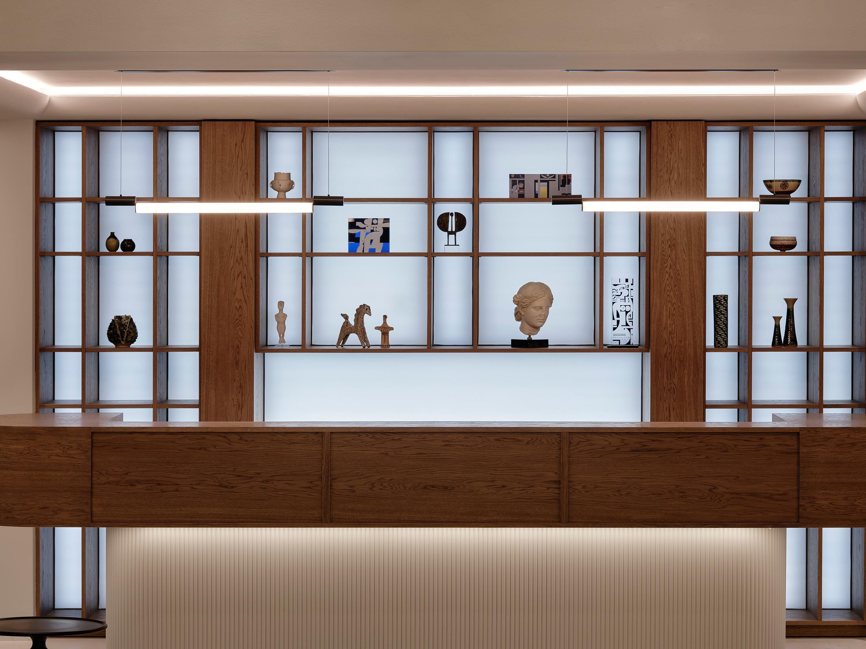 A modern interior with a wooden panel wall, shelves with decorative items, and a bench.