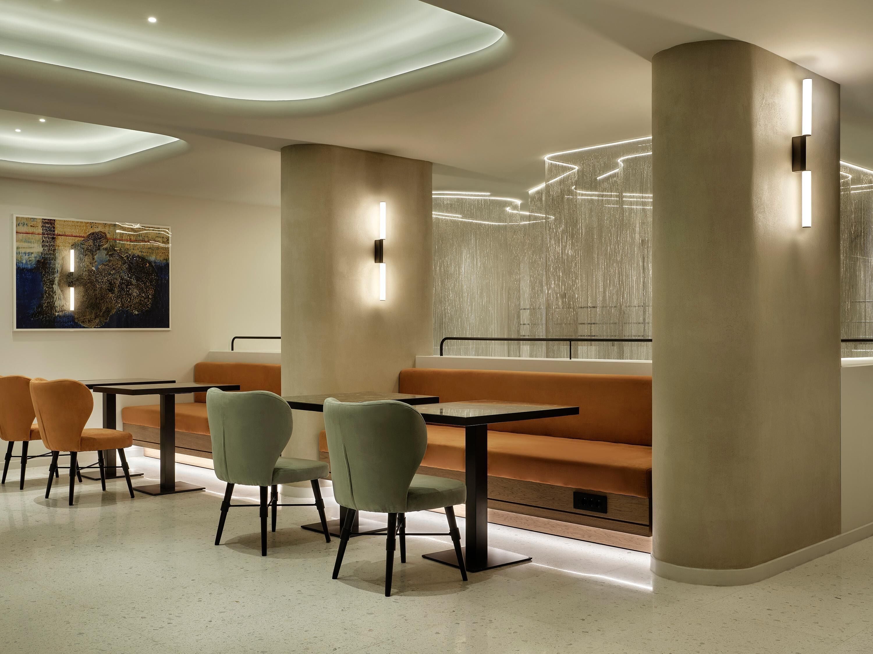 A modern dining area with a high ceiling, recessed lighting, and a large abstract painting on the wall.