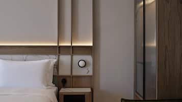 Una habitación de hotel con cama, mesita de noche, un reloj en la pared y detalles de panel de madera.