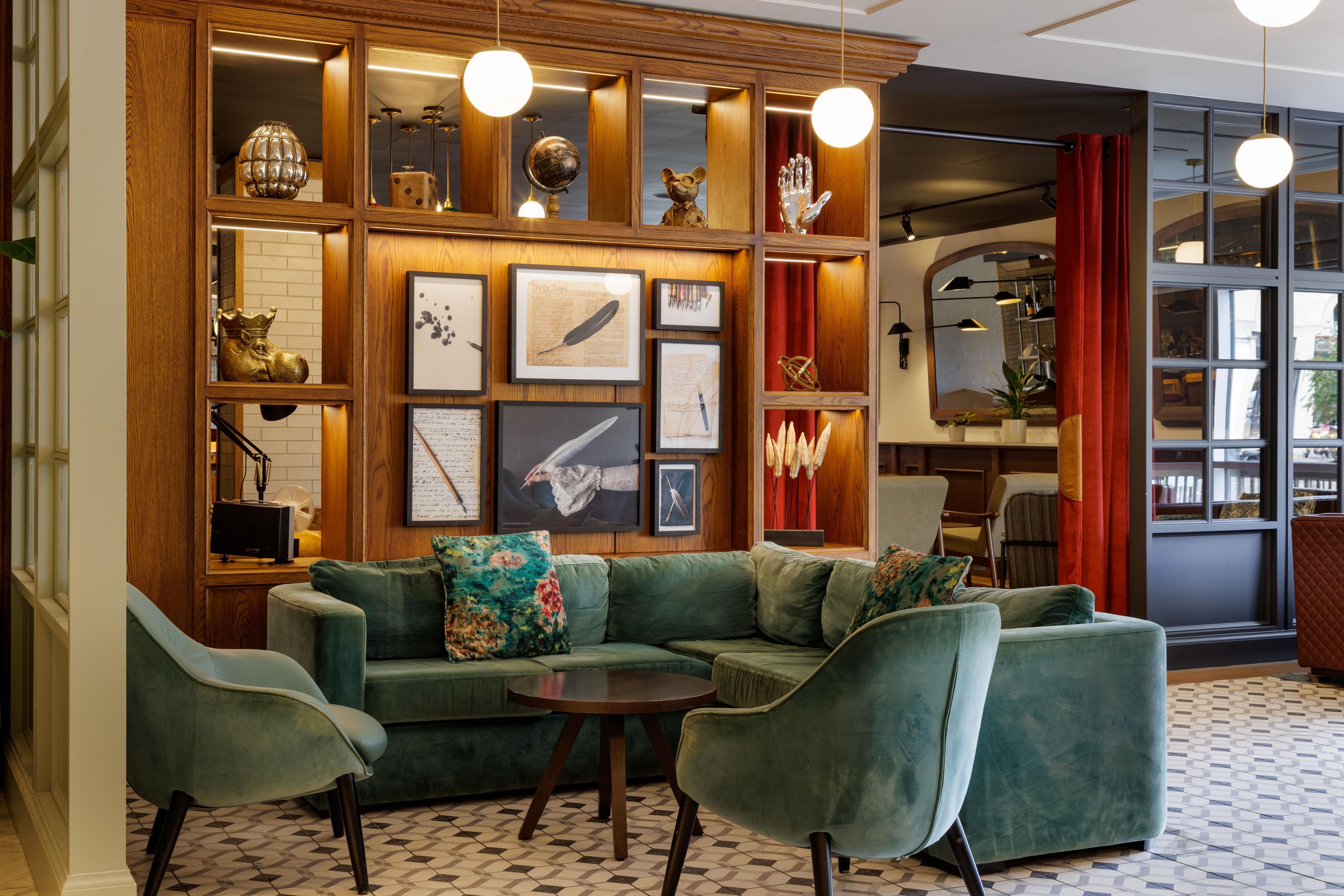A modern interior with a green sectional sofa, a small round table, and a decorative wall with various items.