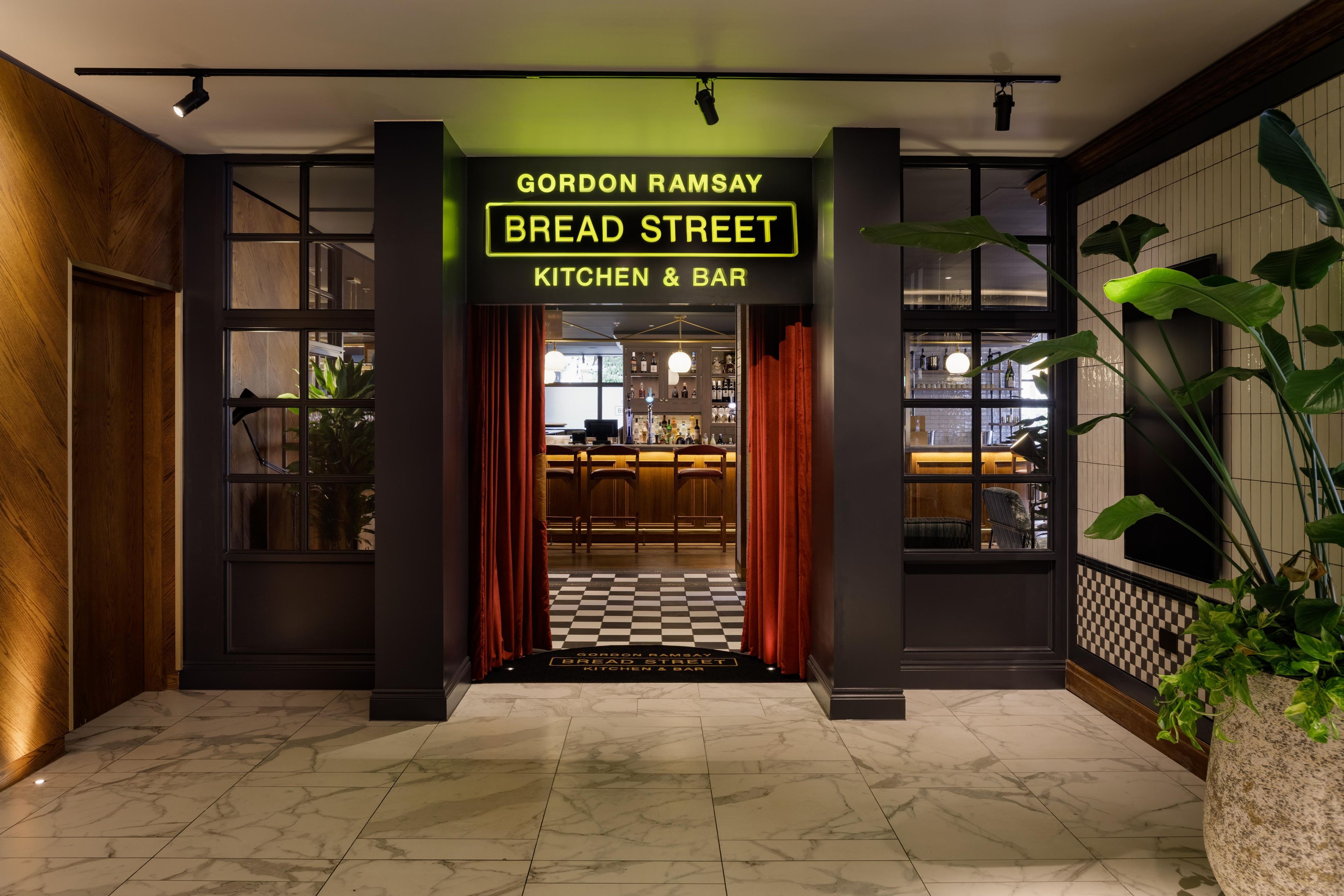 A restaurant entrance with a neon sign reading 'Gordon Ramsay Bread Street Kitchen & Bar'.