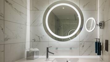 A modern bathroom with a large mirror, a sink, and a shower.