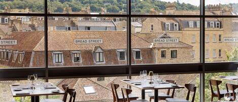 Un restaurant offrant une vue sur Bread Street, avec des tables et des chaises disposées pour accueillir les clients.