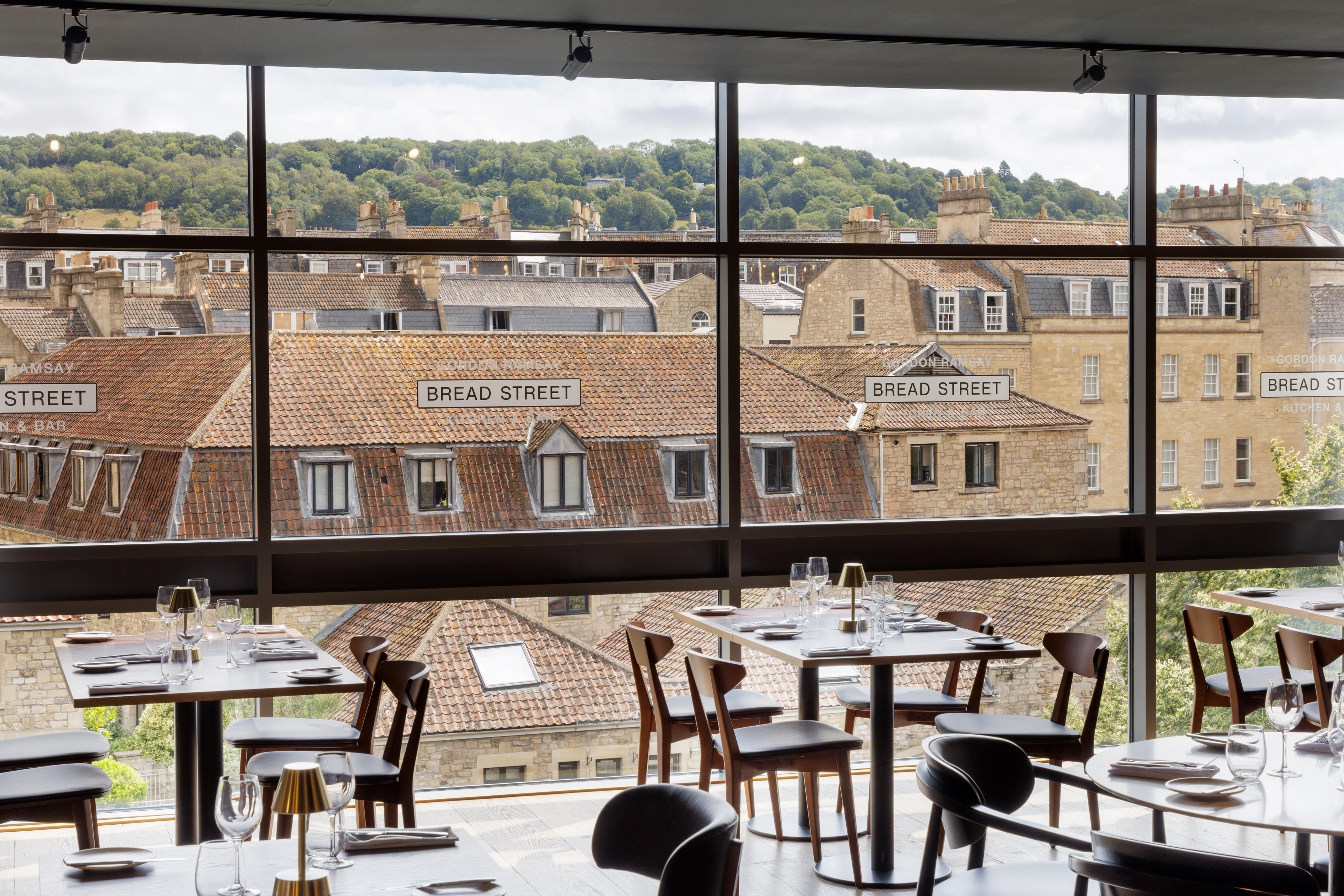 A restaurant with a view of Bread Street, featuring tables and chairs set for dining.