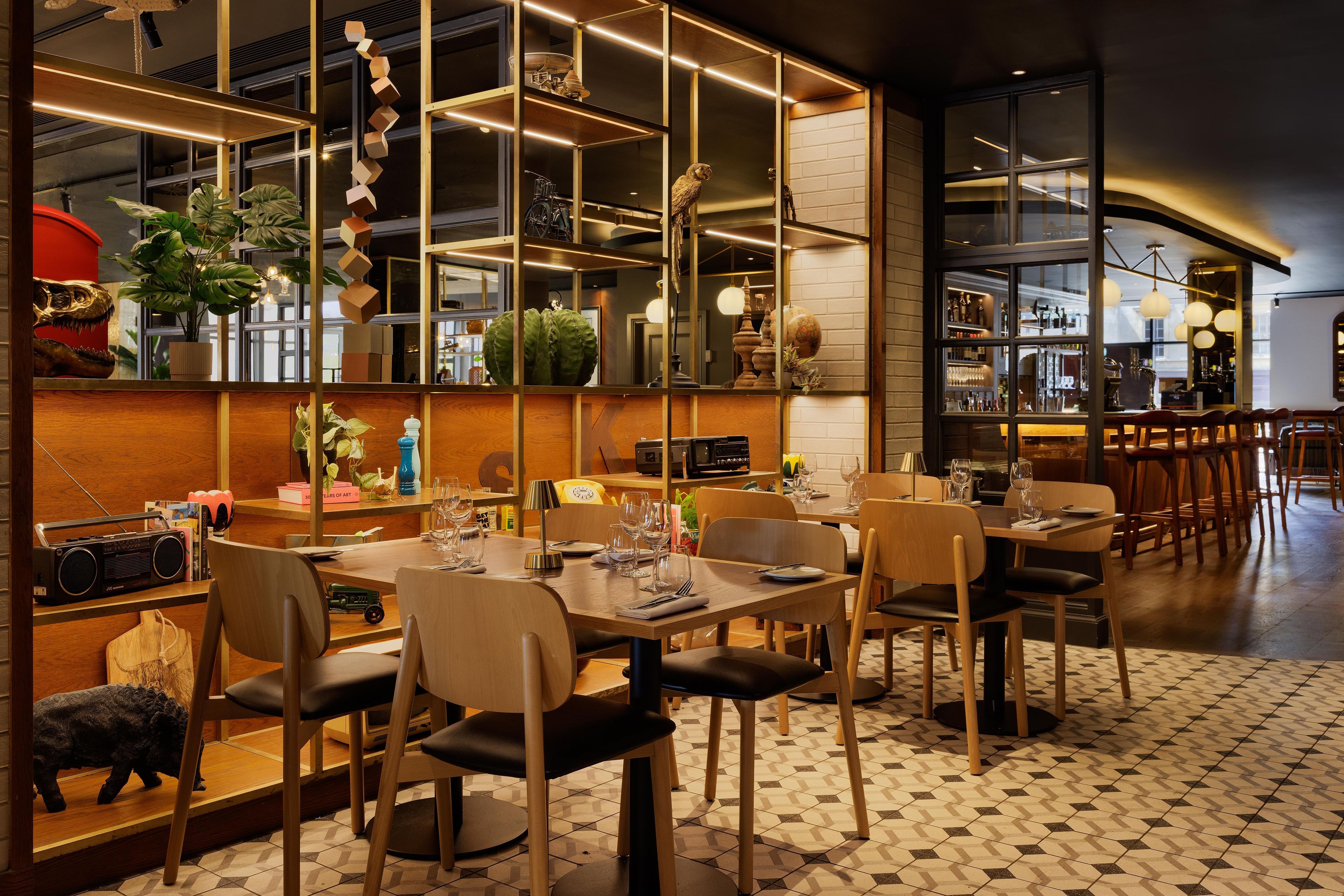 A restaurant with a modern interior, featuring a bar area with a mirrored wall, wooden furniture, and a variety of decorative items.
