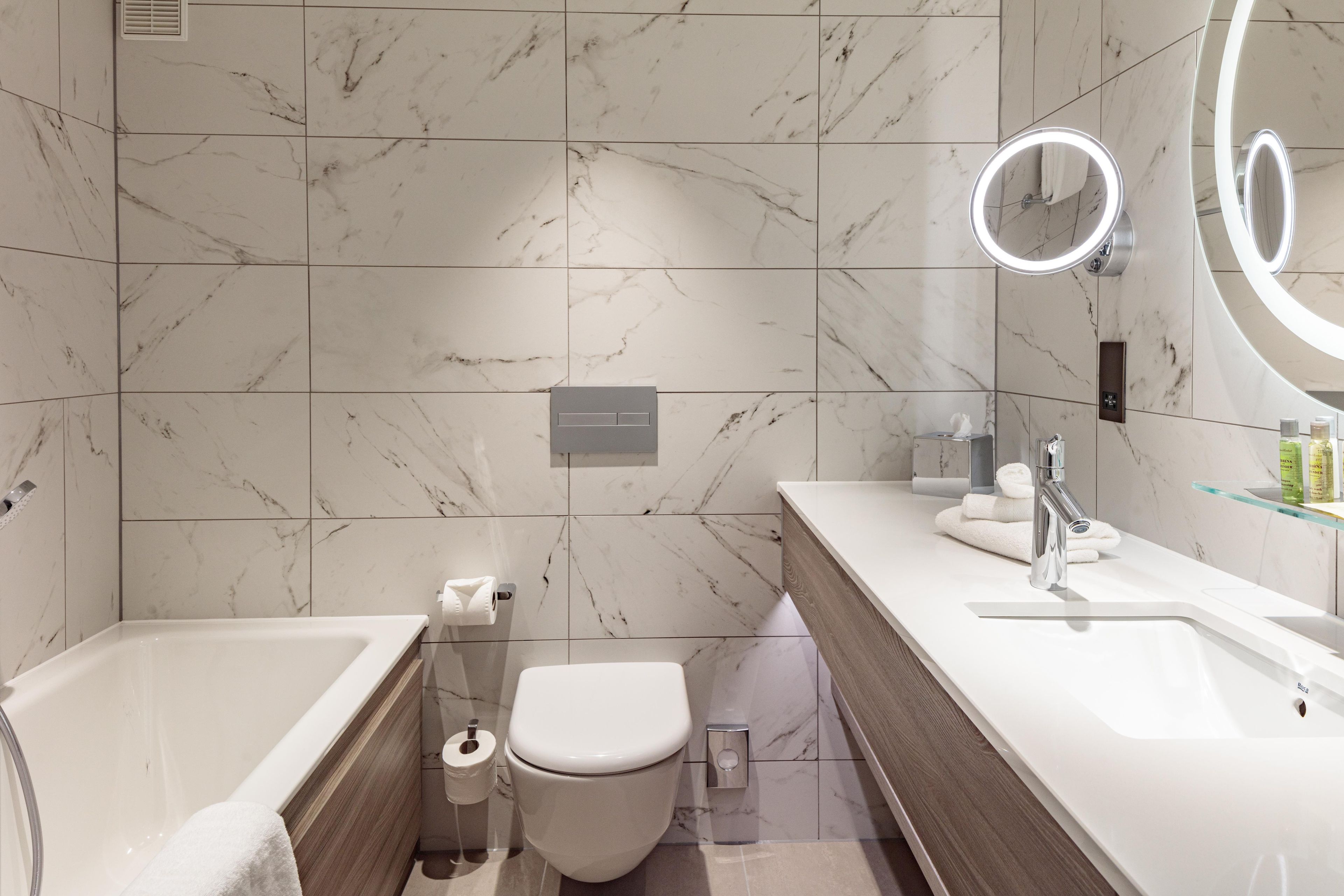 Un baño moderno con bañera, inodoro y tocador con espejo.
