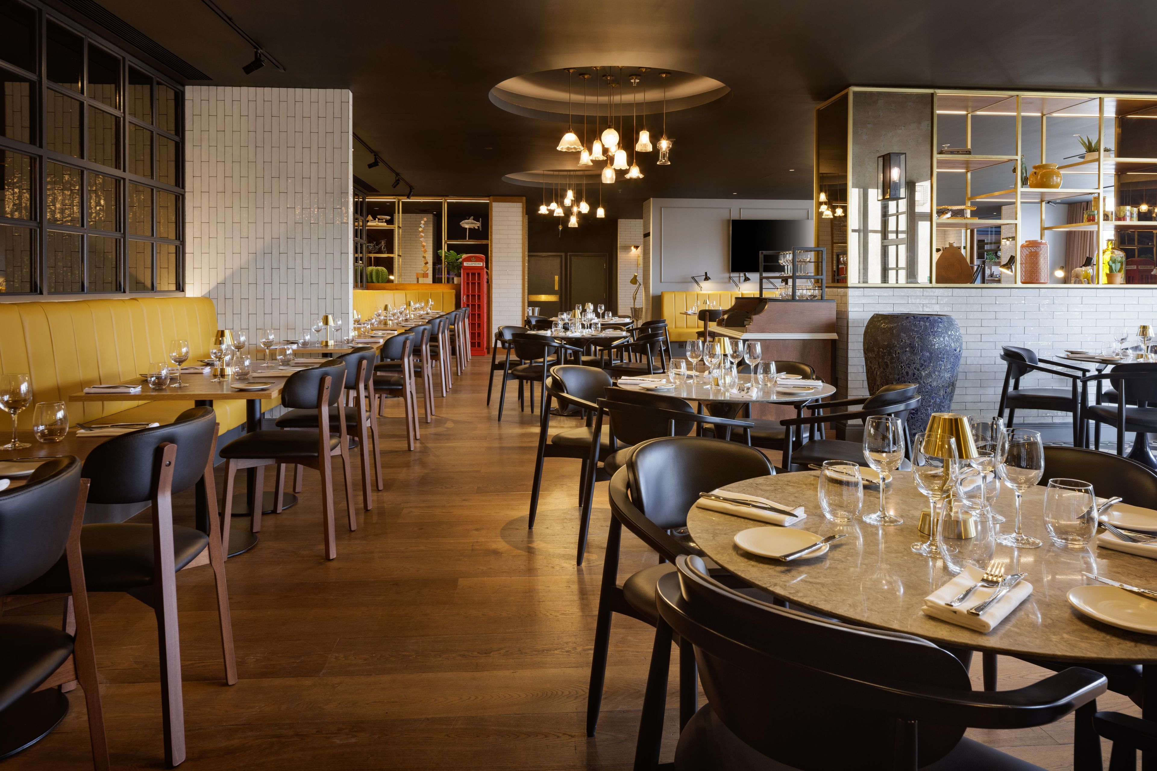 A restaurant interior with multiple dining tables, chairs, and hanging pendant lights.