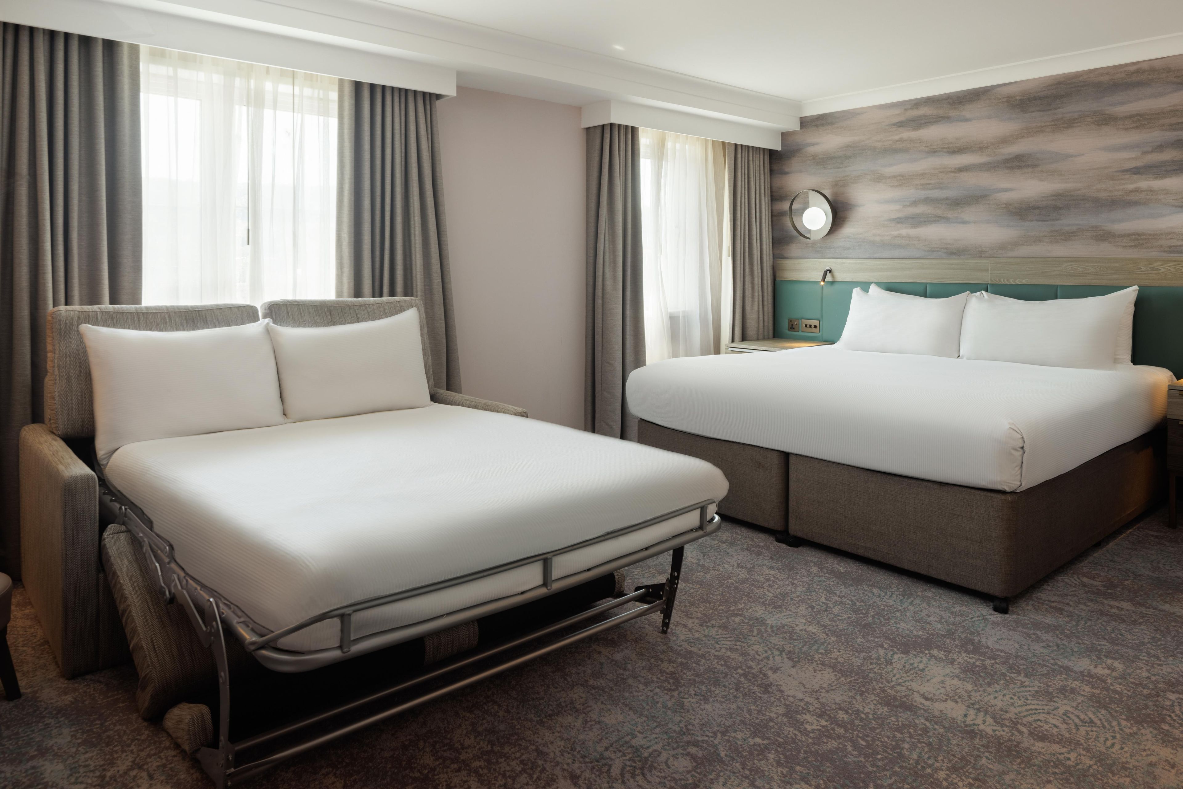 A hotel room with a bed, a sofa, and a nightstand.