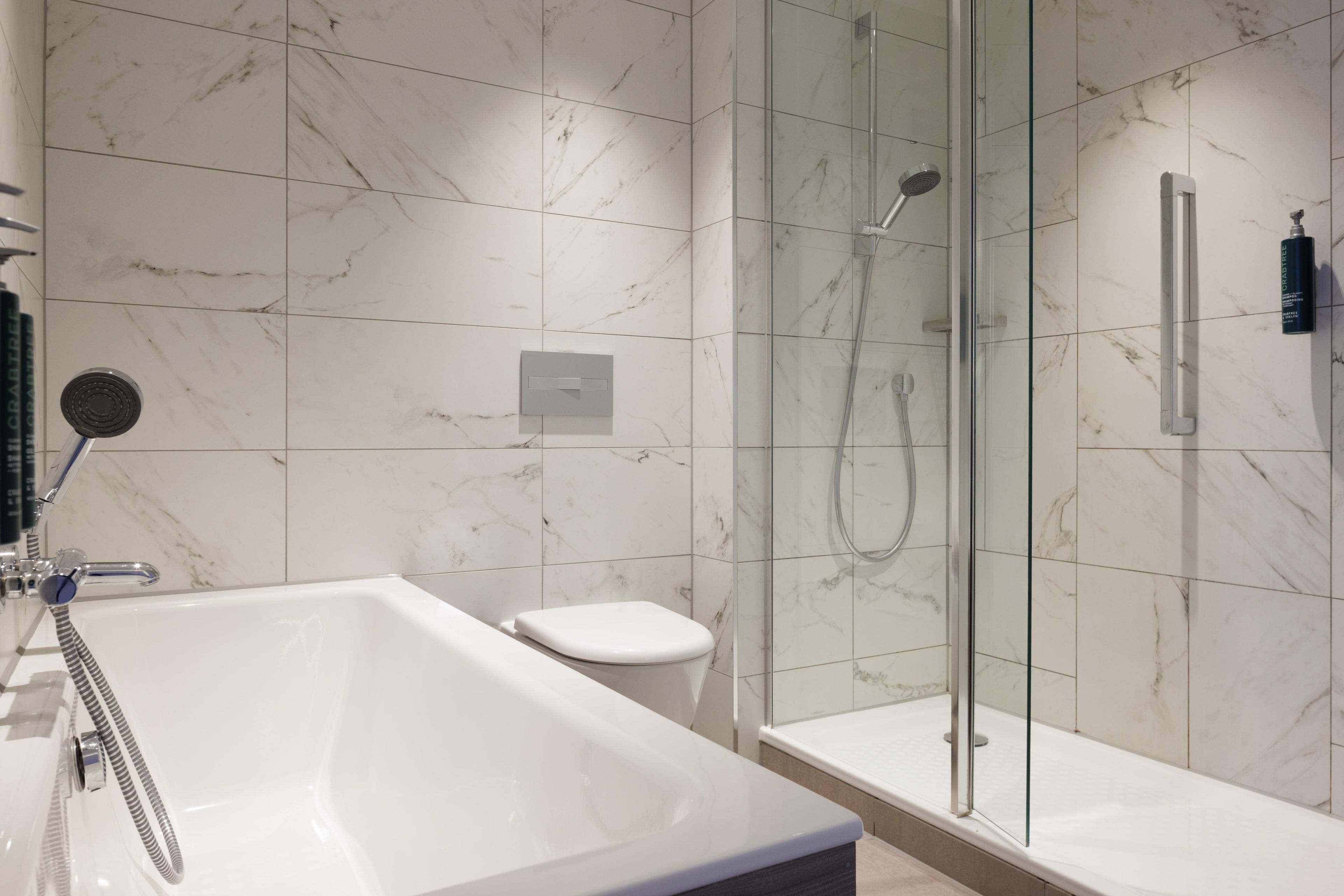 Een moderne badkamer met een douche in een glazen cabine, een vrijstaand bad en een toilet.