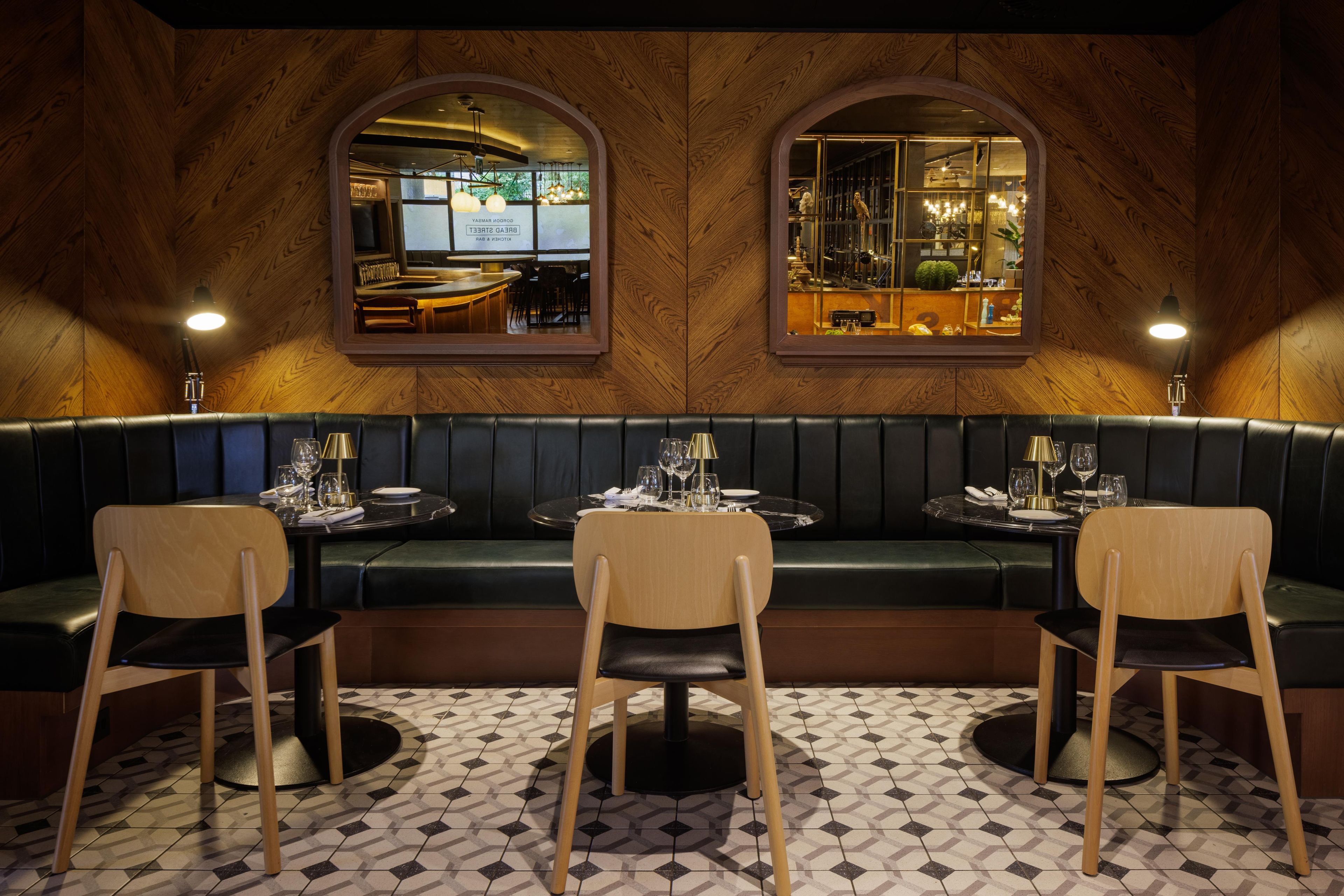 A restaurant with a wooden interior, a green booth seating area, and a tiled floor.