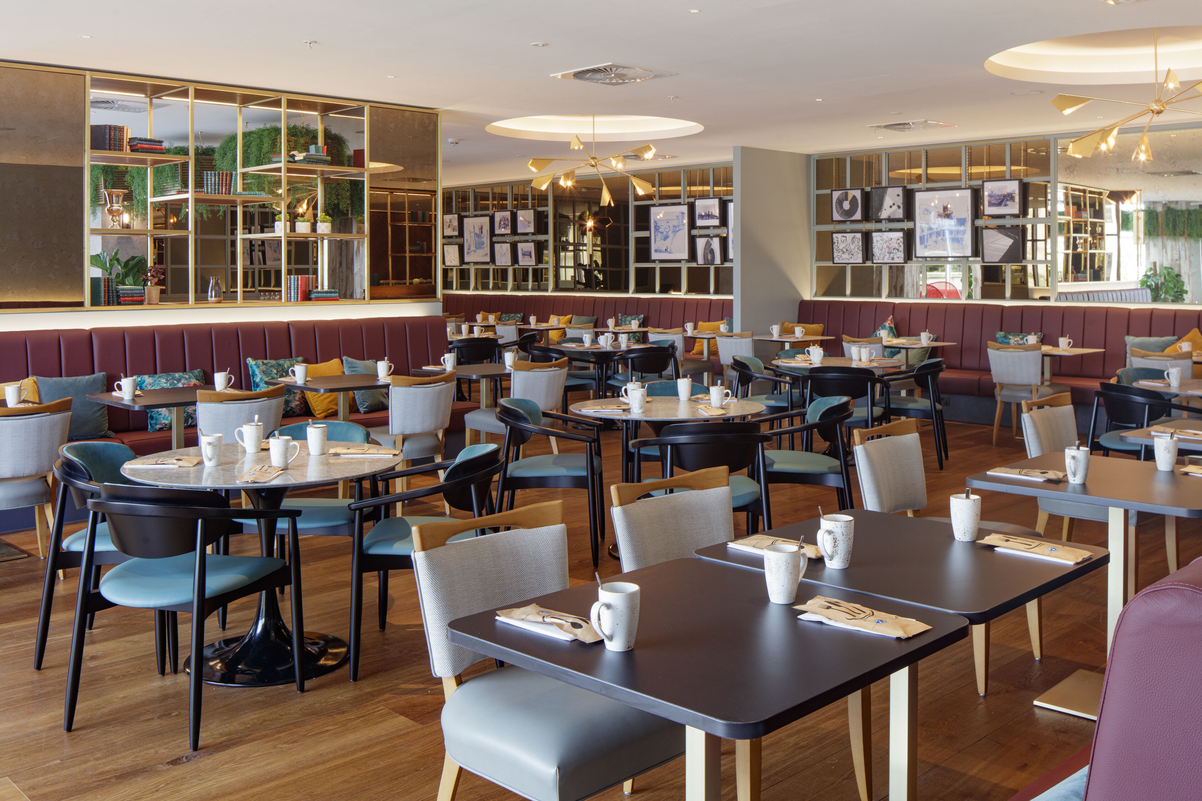 A modern cafe with multiple seating areas, including booths and tables, and a variety of chairs.