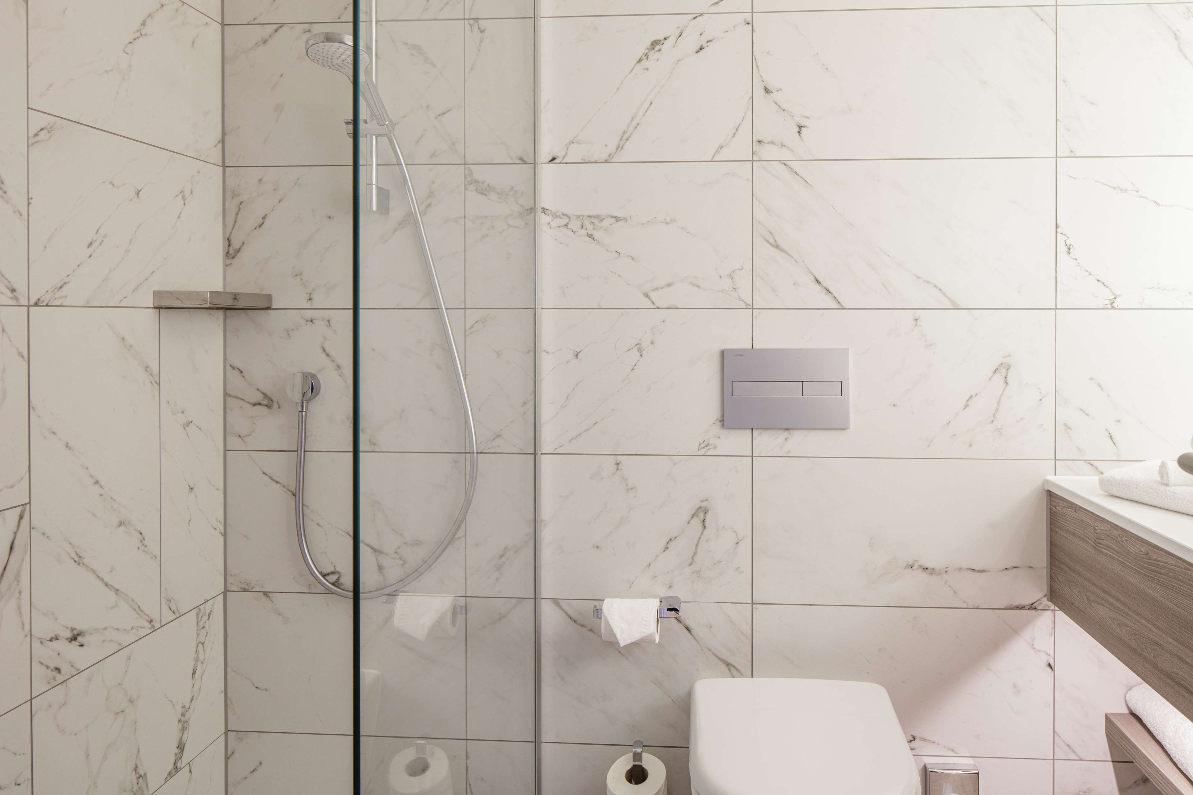 Une salle de bain avec une douche à parois de verre, des toilettes et un lavabo avec une serviette.