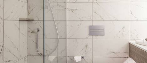 A bathroom with a glass-enclosed shower, a toilet, and a sink with a towel.