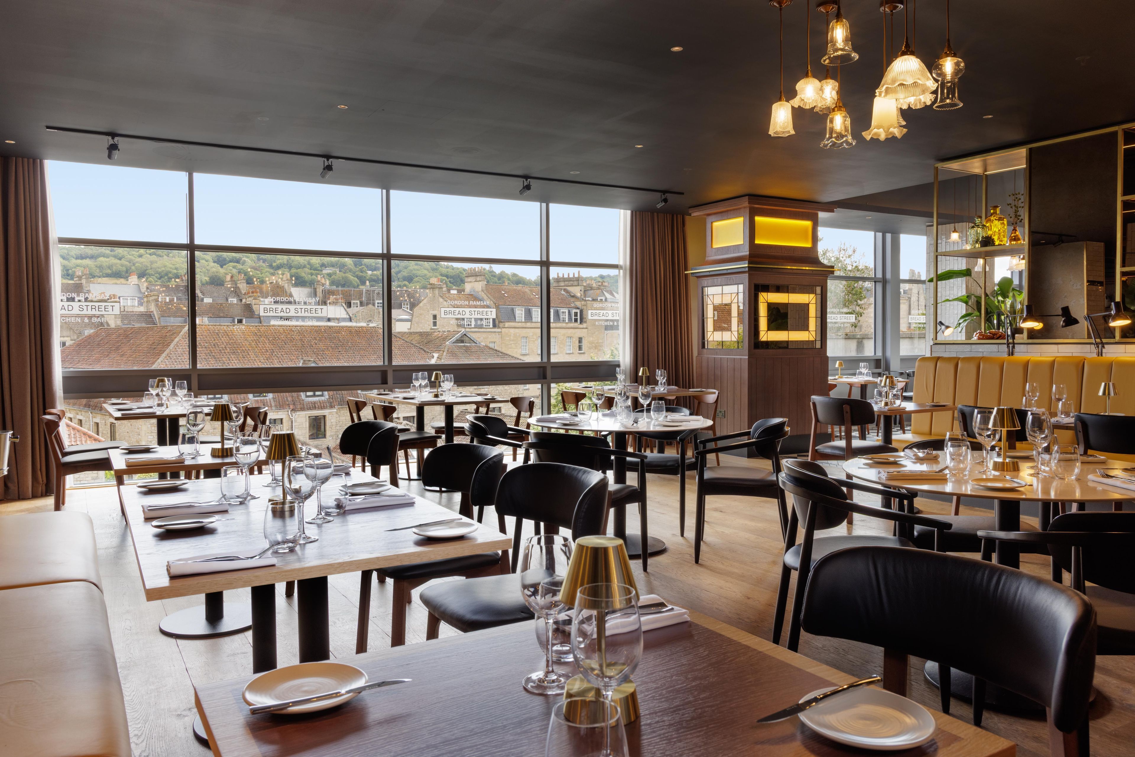 A restaurant with multiple dining tables, chairs, and a view of the city through large windows.