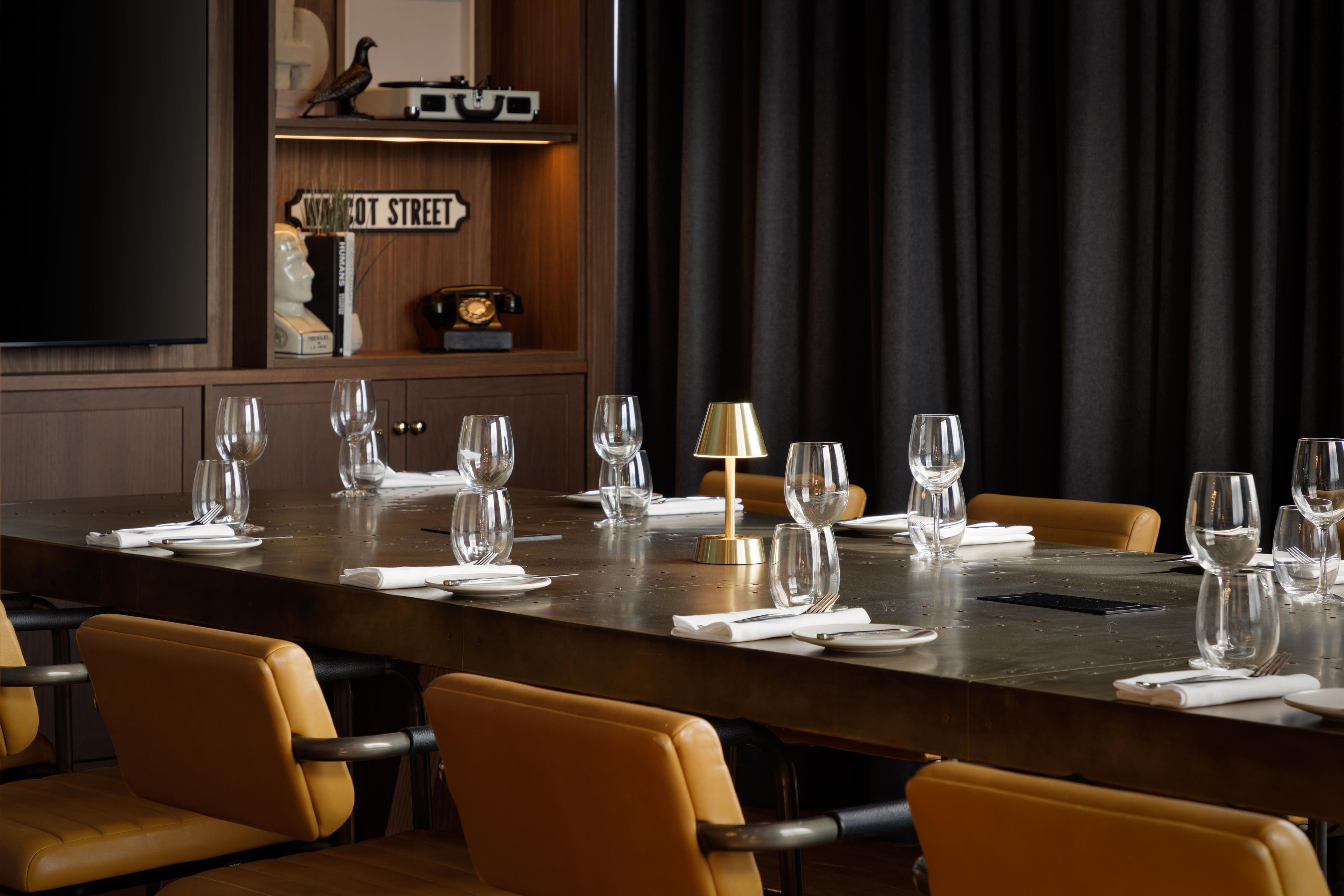 A conference room with a long table set for a meeting, surrounded by chairs.