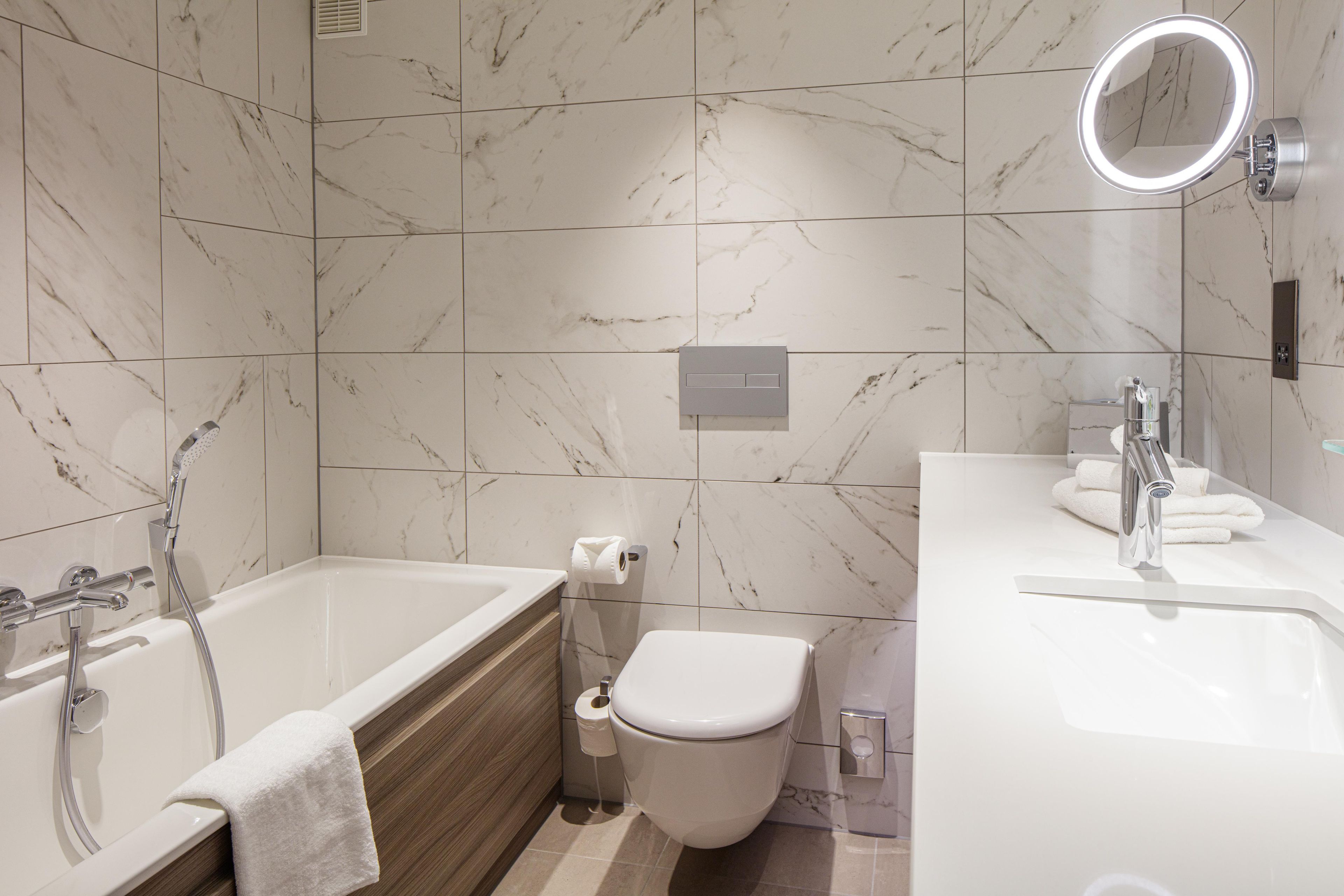 Une salle de bain moderne équipée d’une baignoire, de toilettes et d’un lavabo.