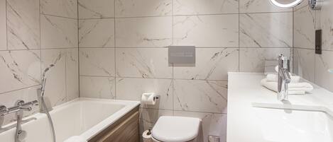 Une salle de bain moderne équipée d’une baignoire, de toilettes et d’un lavabo.