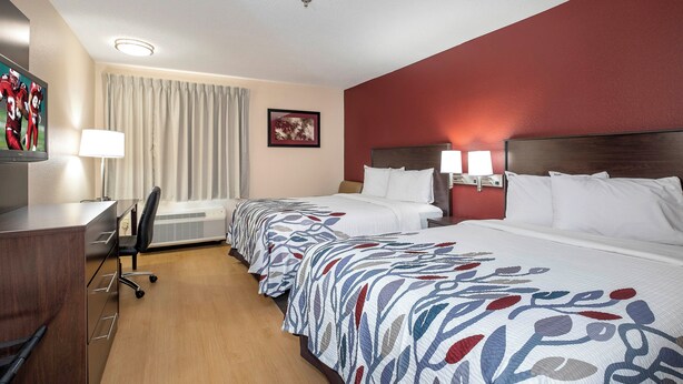 A hotel room with two beds, a desk, a chair, and a window with curtains. - Red Roof Inn Raleigh Southwest - Cary (Cary)