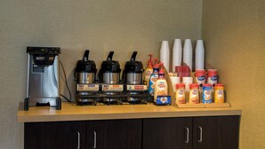 A coffee station with a coffee machine, multiple coffee dispensers, and a selection of coffee creamer bottles. - Red Roof Inn Raleigh Southwest - Cary (Cary)