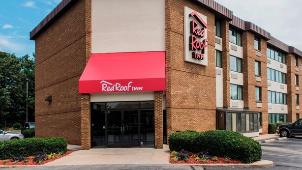 A Red Roof Inn with a red awning, brick facade, and a clear sky. - Red Roof Inn Raleigh Southwest - Cary (Cary)