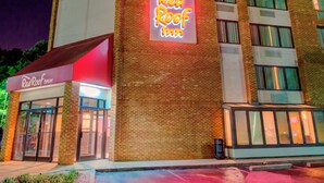 A Red Roof Inn with a prominent neon sign, brick facade, and a glass entrance. - Red Roof Inn Raleigh Southwest - Cary (Cary)