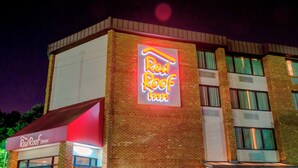 A Red Roof Inn with a prominent neon sign, brick facade, and a glass entrance. - Red Roof Inn Raleigh Southwest - Cary (Cary)