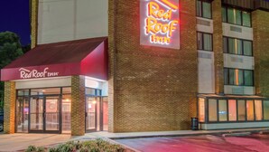 A Red Roof Inn building with a prominent neon sign, a brick facade, and a glass entrance. - Red Roof Inn Raleigh Southwest - Cary (Cary)