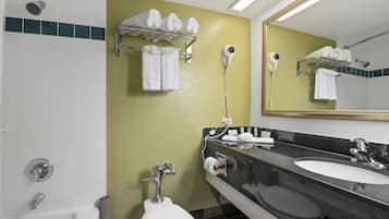 Un baño con una bañera blanca, un lavabo, un inodoro y un espejo. Hay toallas y un secador de pelo en la pared.