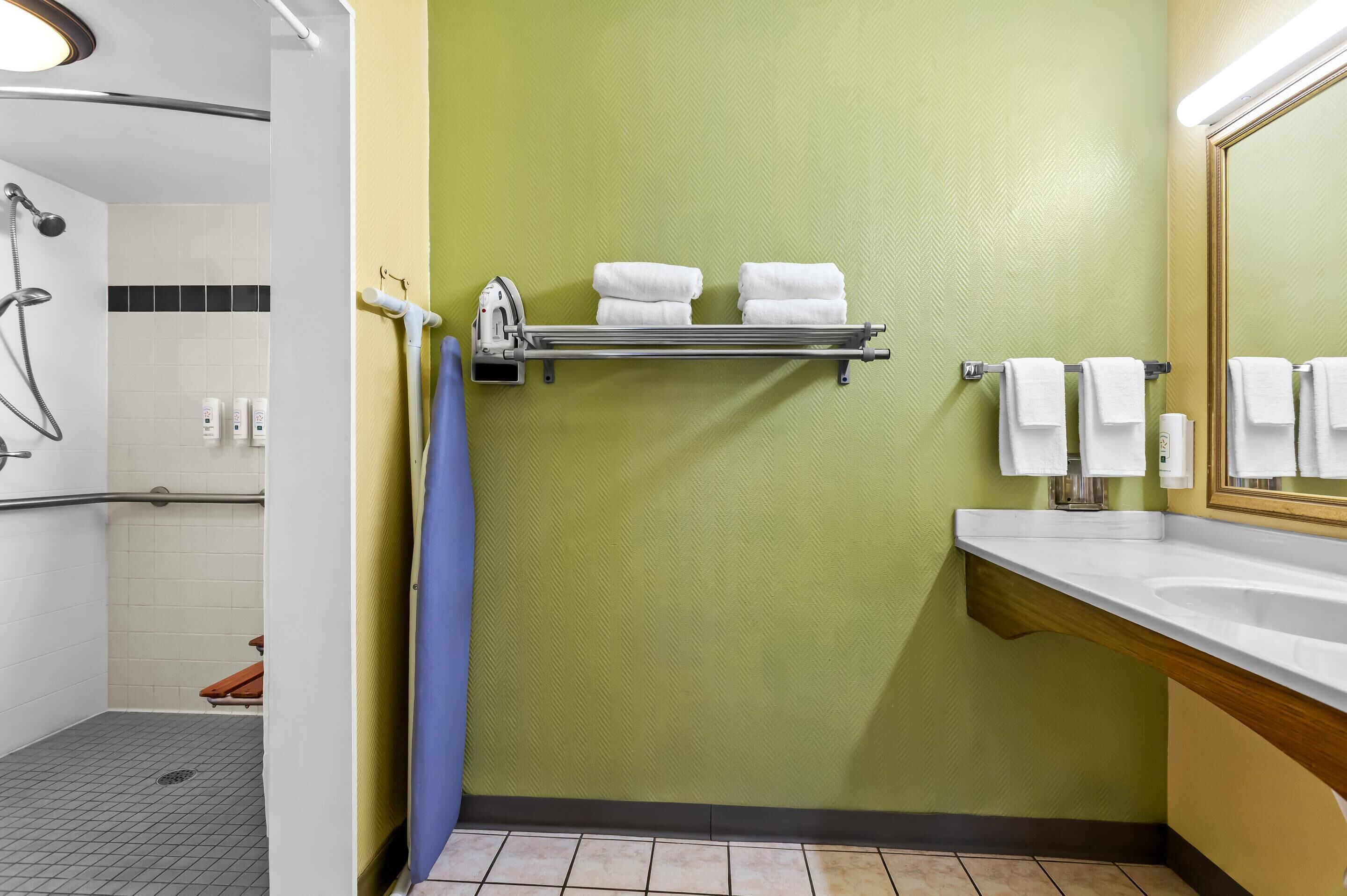 A bathroom with a shower, a sink, and a towel rack.