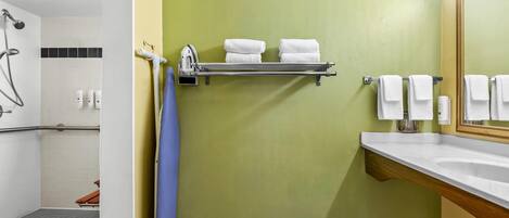 A bathroom with a shower, a sink, and a towel rack.