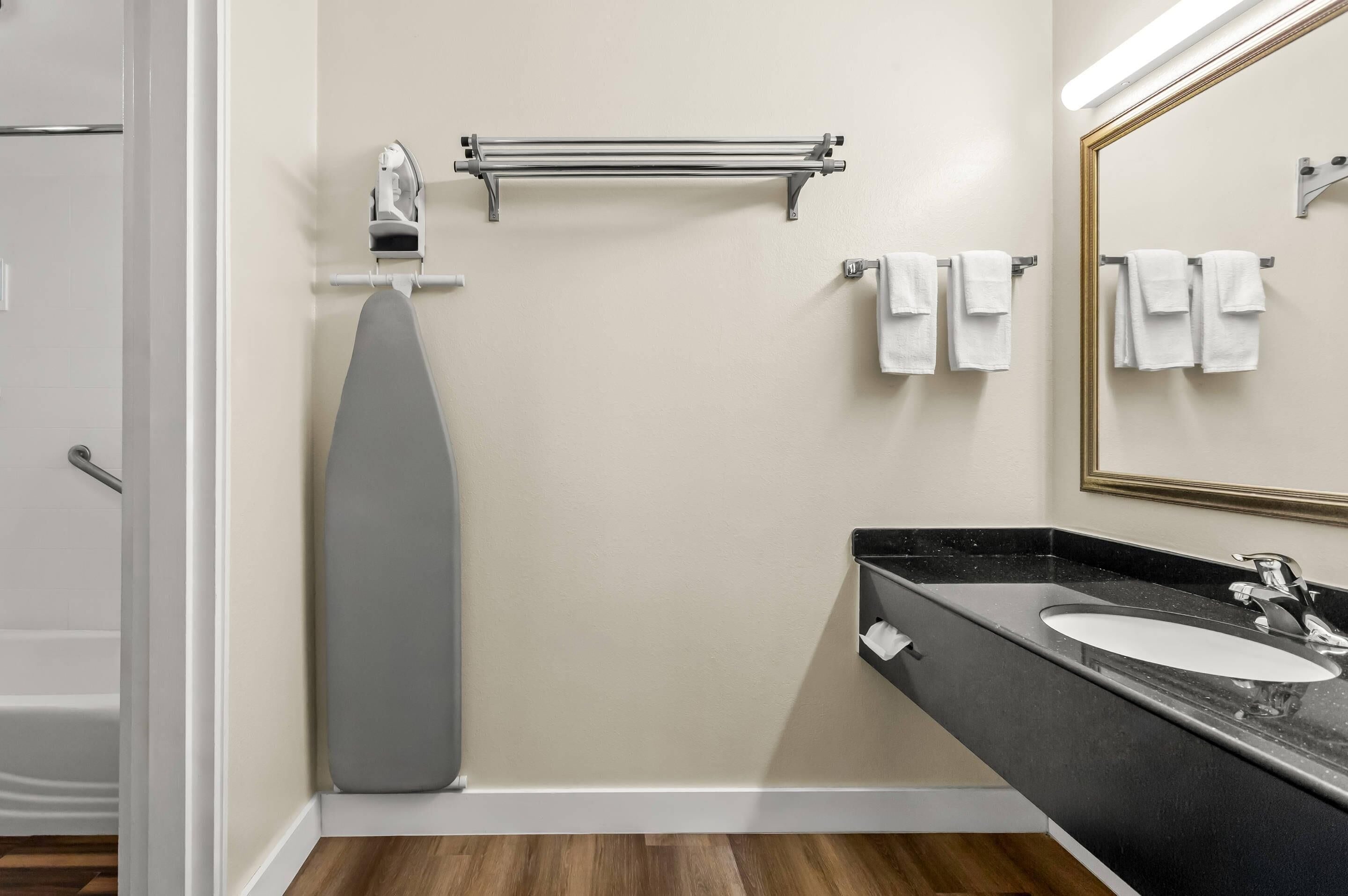 Un baño moderno con bañera, toallero, dispensador de toallas y un espejo grande.