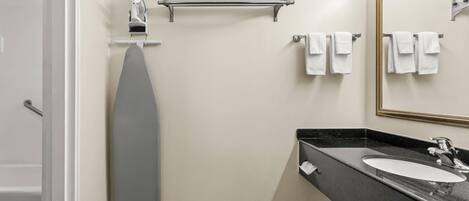 Un baño moderno con bañera, toallero, dispensador de toallas y un espejo grande.