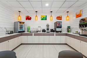 Une cuisine moderne avec des meubles blancs, une machine à café, un réfrigérateur et un grille-pain.