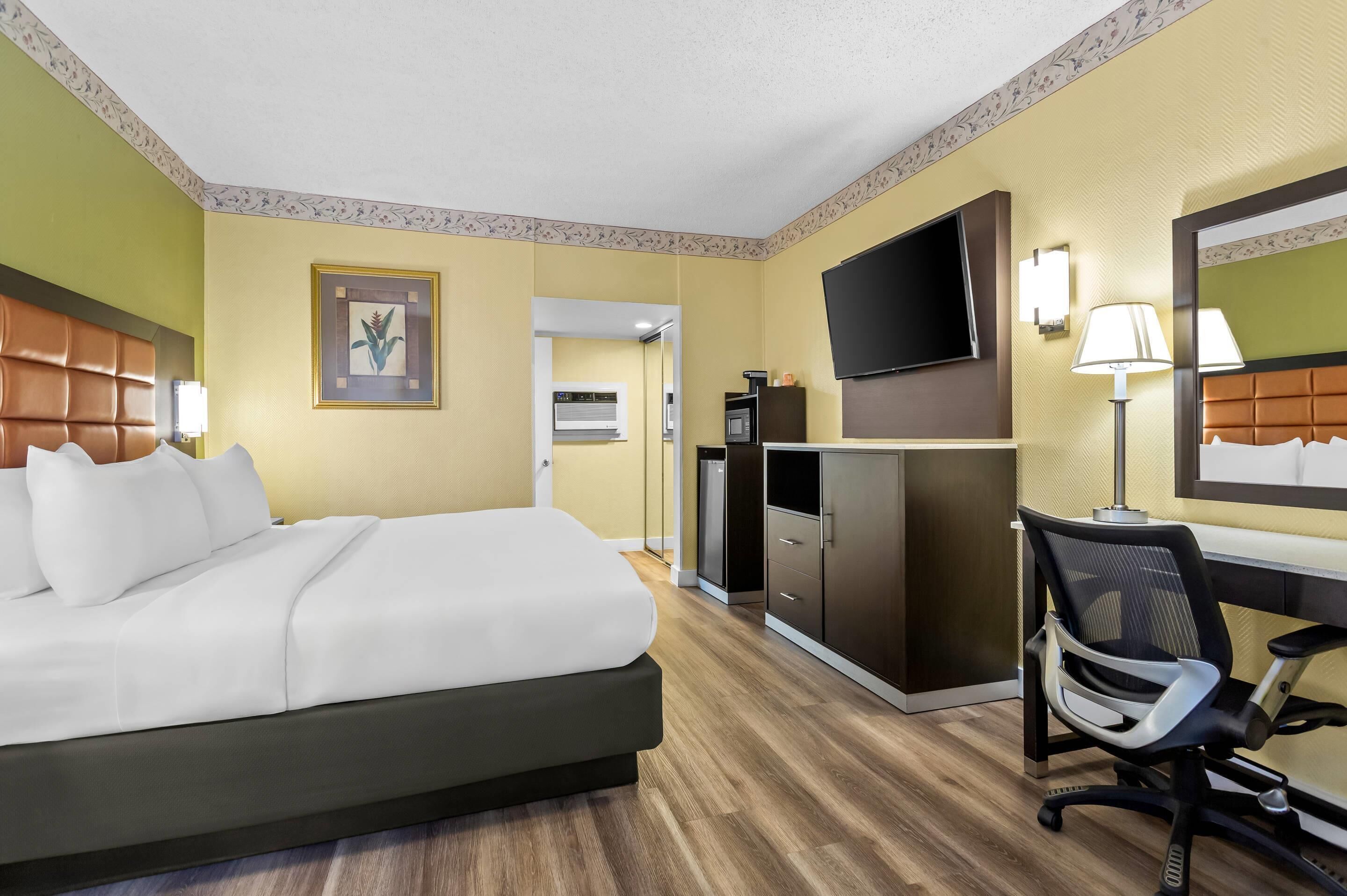 Une chambre d’hôtel équipée d’un lit, d’un bureau, d’une chaise, d’une télévision et d’un miroir.