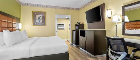 A hotel room with a bed, a desk, a chair, a television, and a mirror.
