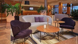 A modern lobby with a reception desk, seating area, and large potted plants. - Dorint City-Hotel Salzburg (Salzburg)