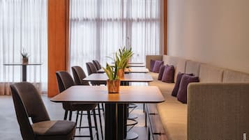 A modern hotel room with a dining area, a sofa, and a small table with plants.