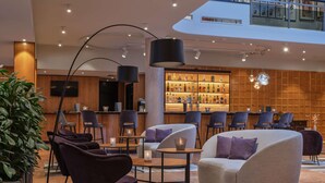 A modern lounge area with seating, a bar, and a large plant. - Dorint City-Hotel Salzburg (Salzburg)