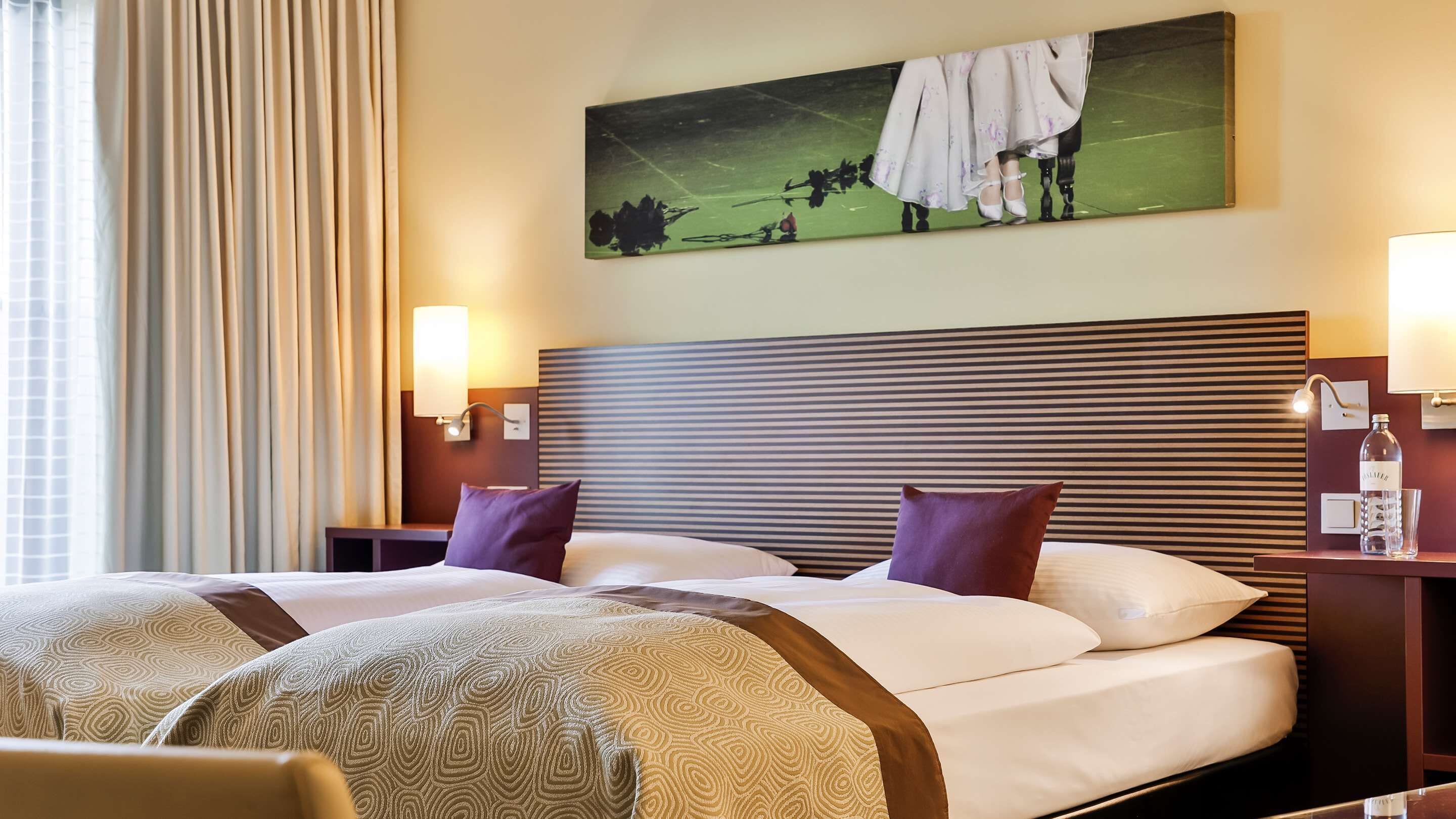 Ein Hotelzimmer mit einem großen Bett, zwei Nachttischen, einem Kopfteil mit horizontalen Linien und einem Gemälde über dem Bett.