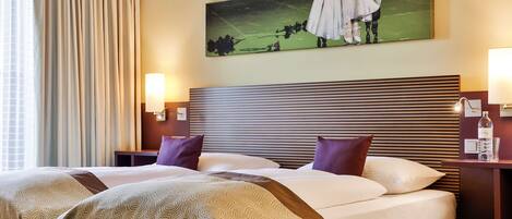 Ein Hotelzimmer mit einem großen Bett, zwei Nachttischen, einem Kopfteil mit horizontalen Linien und einem Gemälde über dem Bett.
