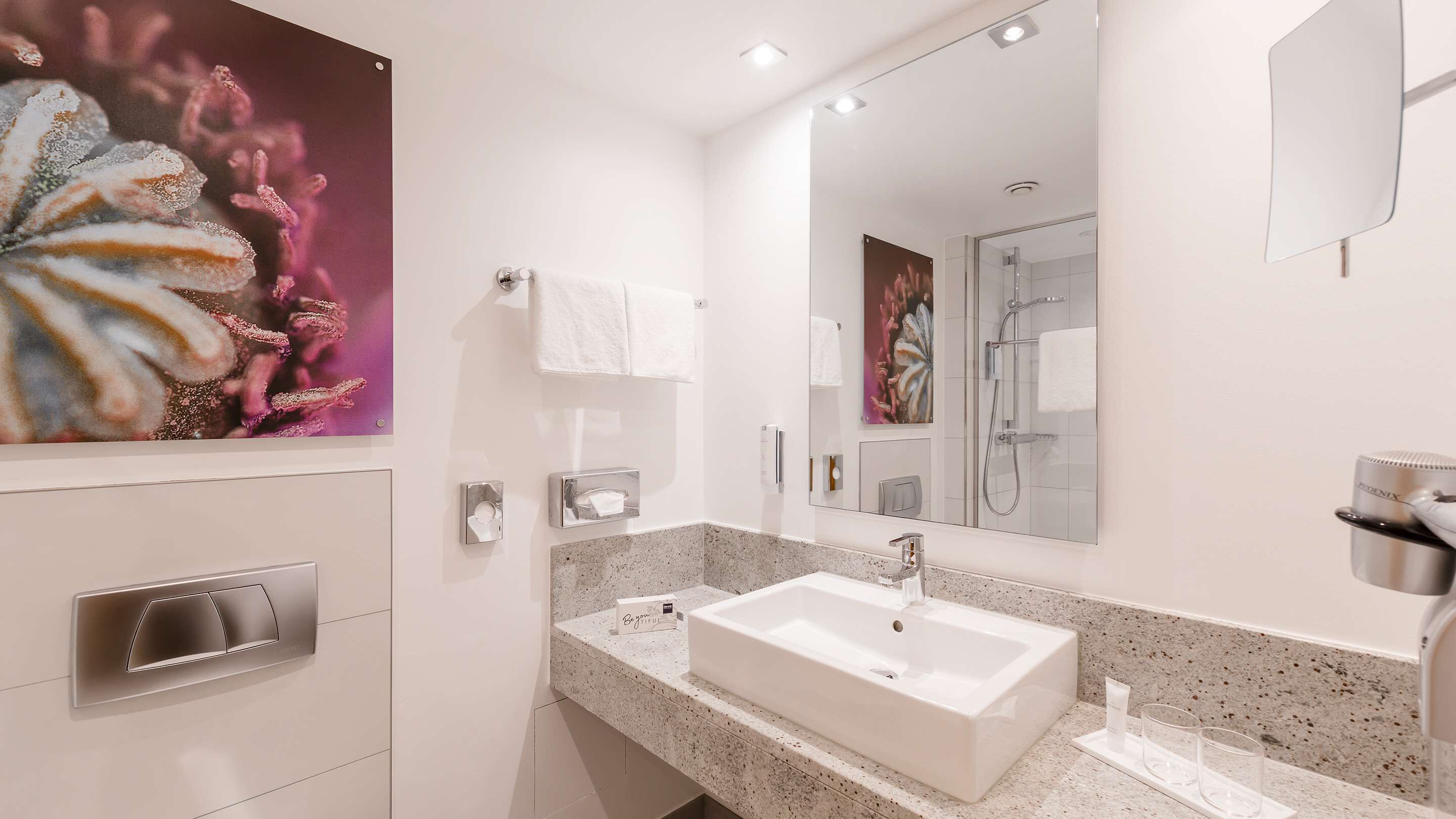 A modern bathroom with a large sink, a mirror, and a shower.